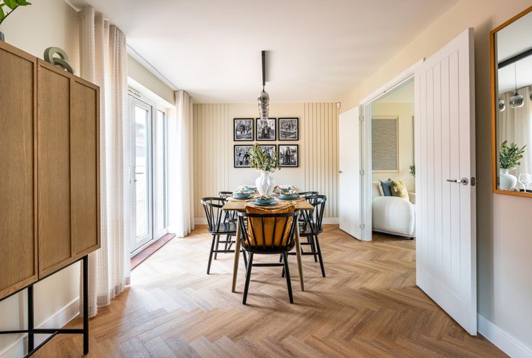 A dining room with a wooden table, chairs, and a pendant light.
