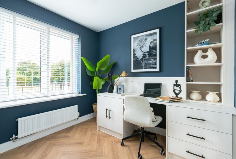 A home office with a desk, chair, laptop, and a bookshelf.