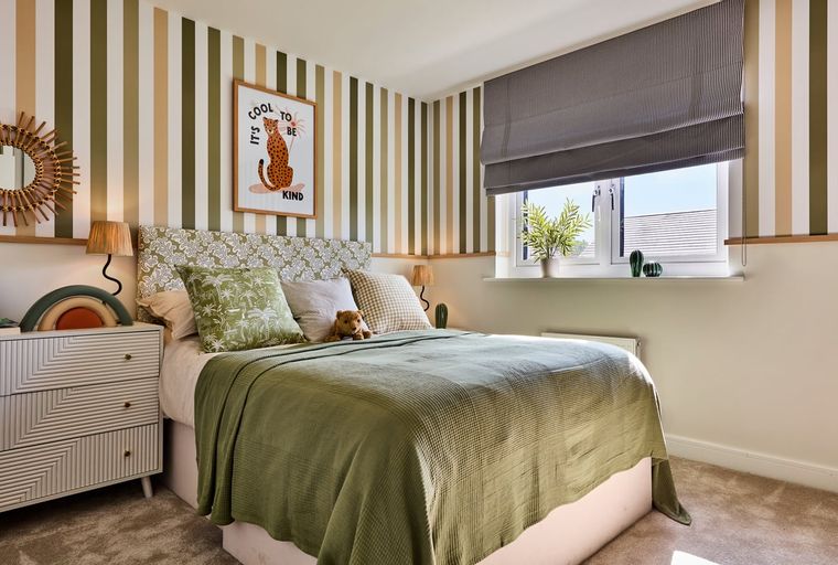 A bedroom with a bed, pillows, a dresser, and a window.