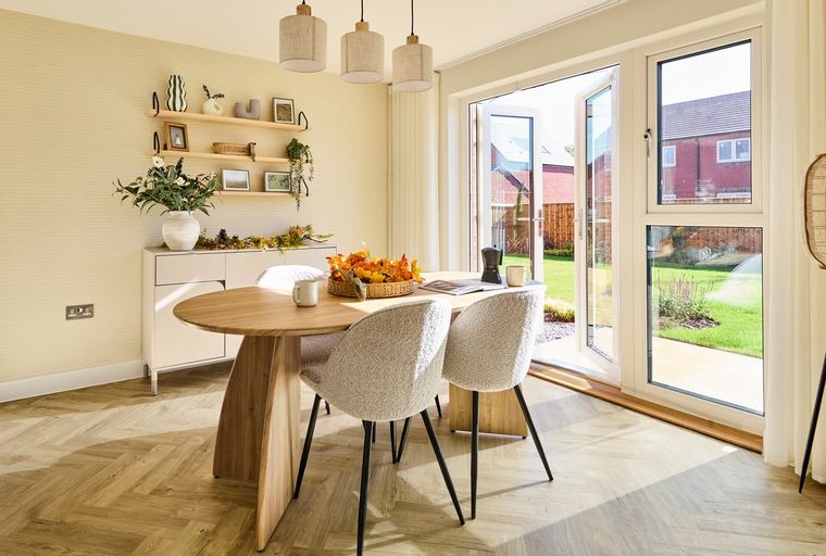 A dining area with a wooden table, chairs, and French doors leading to a garden.