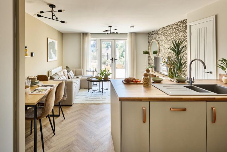 A modern open-concept living, dining, and kitchen area with a sectional sofa, dining table, and kitchen island with a sink.