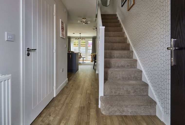 A hallway with a staircase and a view into a dining area.