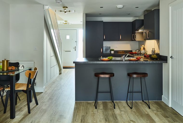 A modern kitchen and dining area with a staircase and front door.
