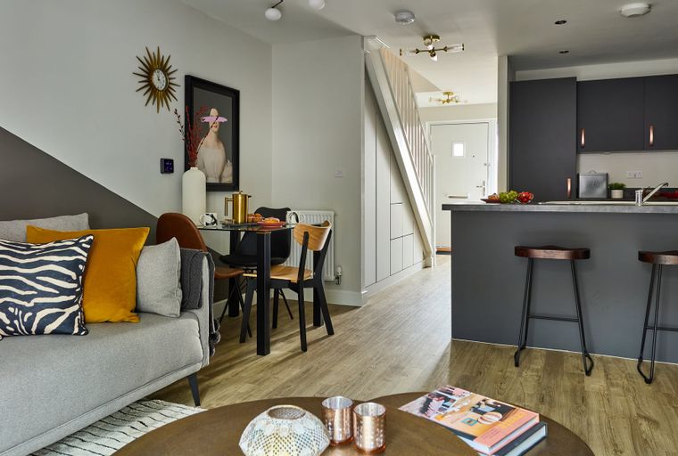 A living room and kitchen area with a sofa, dining table, and kitchen island.