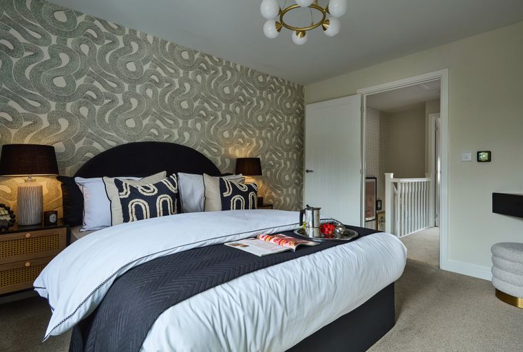 A bedroom with a bed, pillows, lamps, and a tray with a coffee maker.