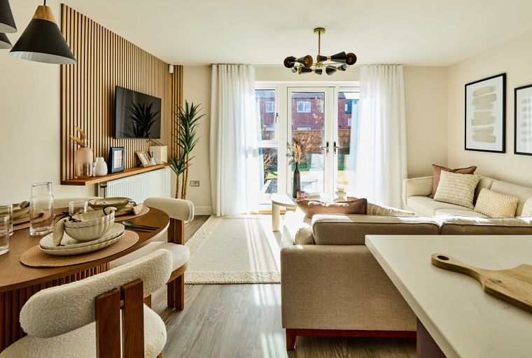 A dining and living area with a wooden slatted wall, a TV, a dining table, and a sectional sofa.