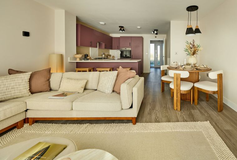 A living room and kitchen area with a sectional sofa, dining table, and kitchen island.