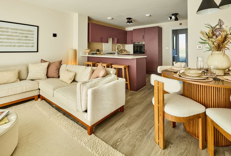 A living room and kitchen area with a sectional sofa, kitchen island with stools, and a dining table with chairs.