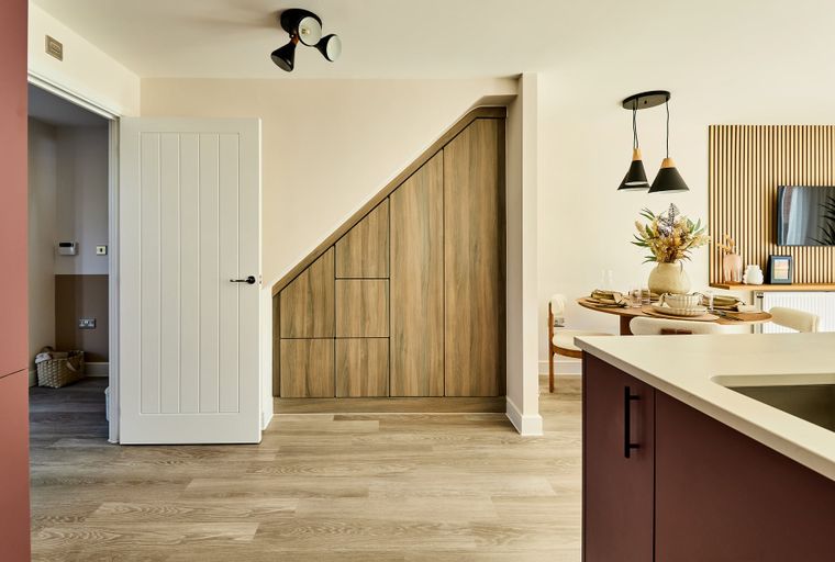 A hallway with a white door, under-stair storage, and a dining area with a table and chairs.