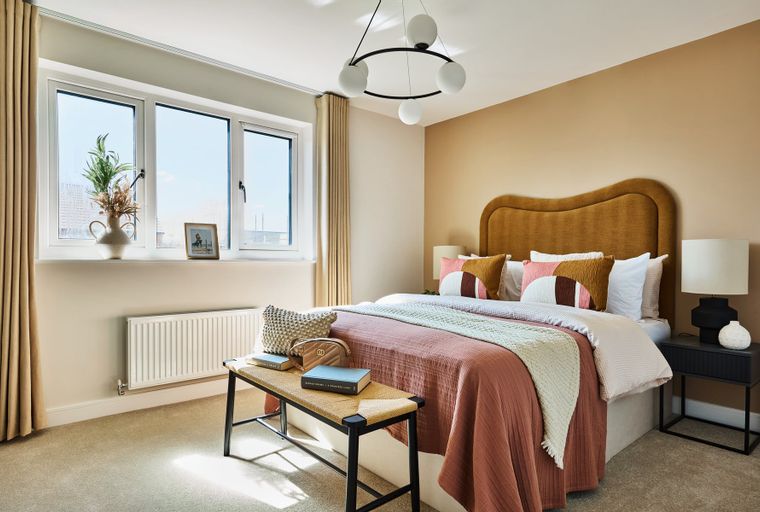 A bedroom with a bed, pillows, a headboard, a window, and a bench.