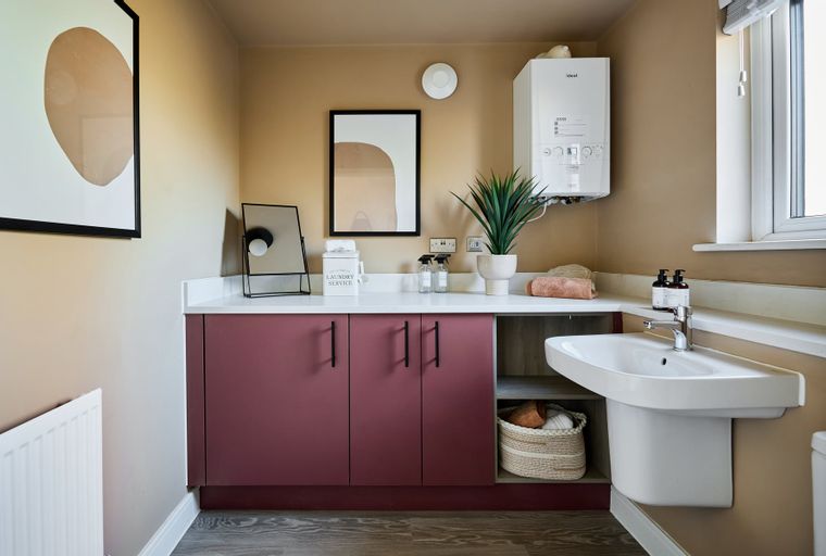 A laundry room with a sink, cabinetry, and a wall-mounted boiler.