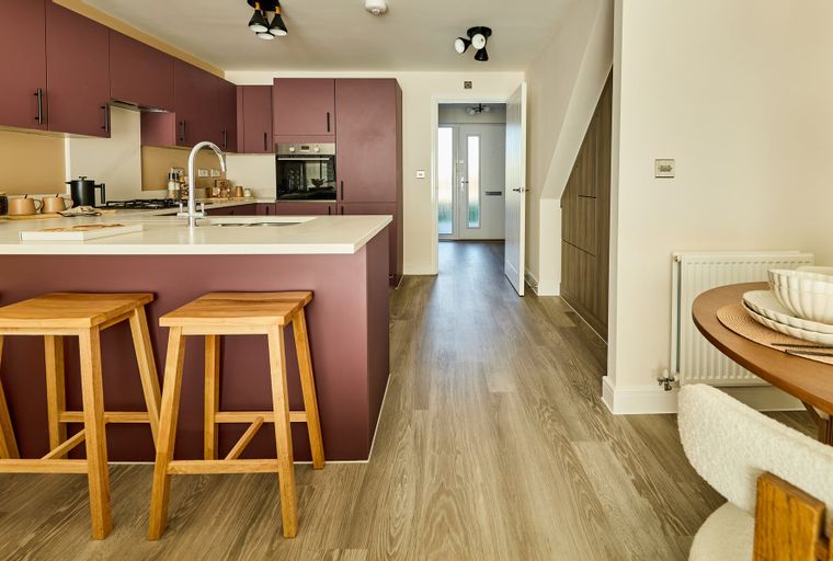 A modern kitchen and dining area with plum cabinets, a kitchen island with stools, and a round dining table.