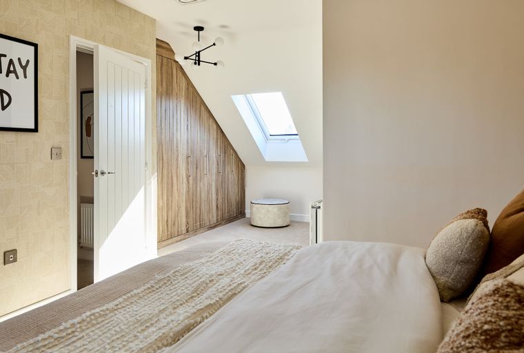 A bedroom with a bed, built-in wardrobes, a skylight, and a chandelier.