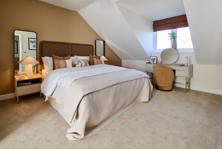 A bedroom with a bed, nightstand, vanity, and chair.