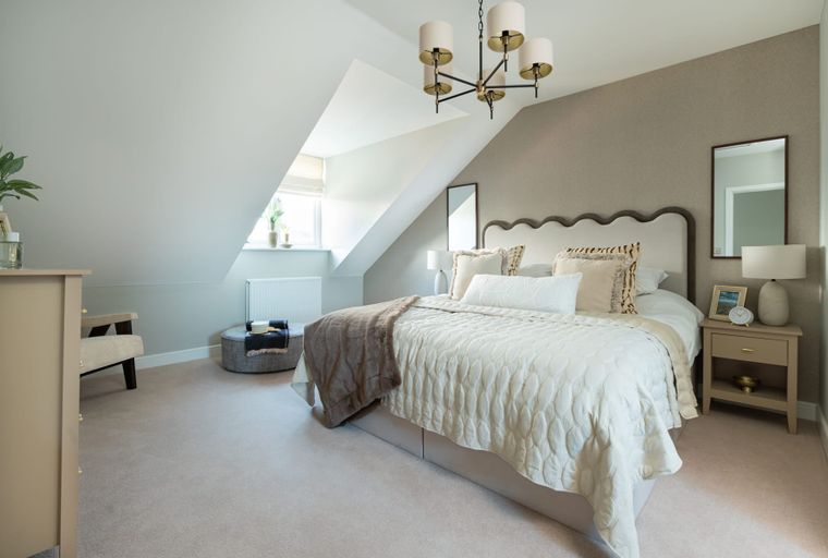 A bedroom with a bed, bedside tables, and a chandelier.