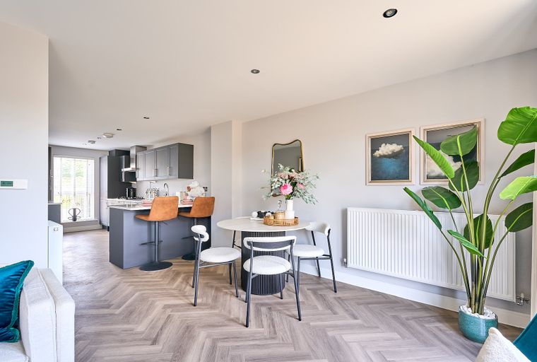A dining area and kitchen with bar stools and a round table.