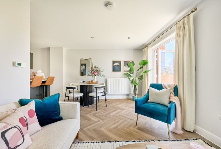 A living and dining area with a sofa, chairs, a dining table, and a large window.