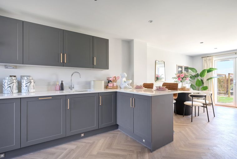 A modern kitchen with grey cabinets, a sink, and a dining area.