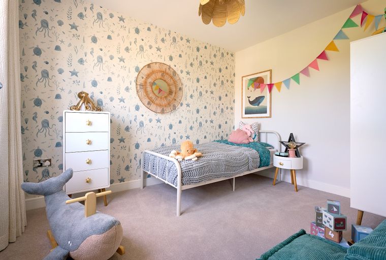 A child's bedroom with a bed, dresser, and ocean-themed wallpaper.