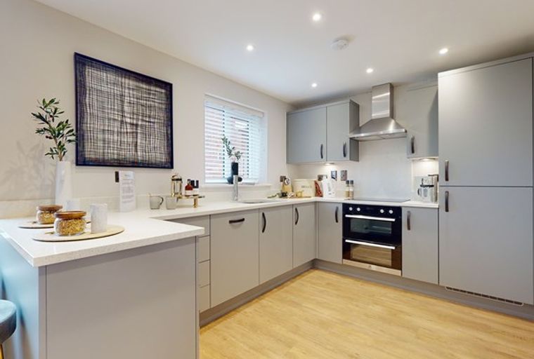 A modern kitchen with grey cabinets, countertops, and a built-in oven.