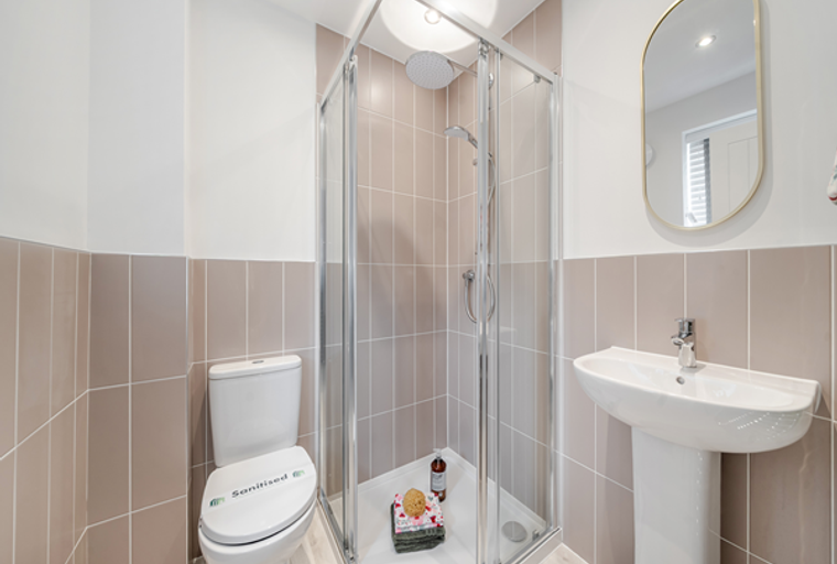 A bathroom with a toilet, shower enclosure, and a sink.