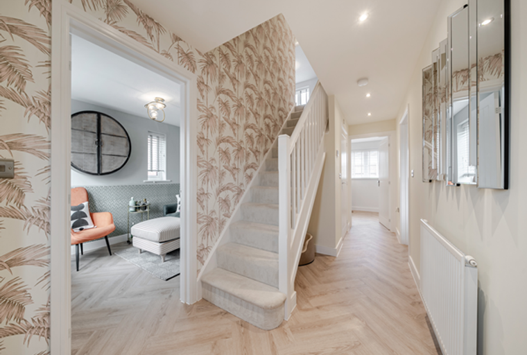 A hallway with a staircase, wallpaper, and a mirror.