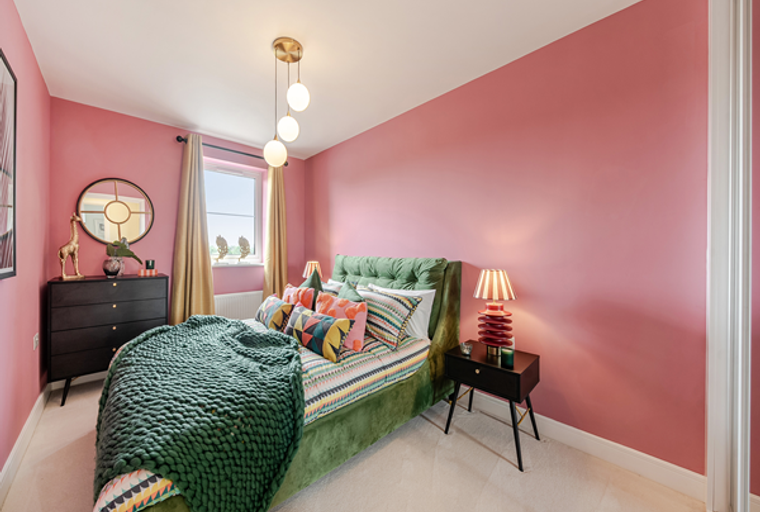 A bedroom with a green bed, pink walls, and a dresser.
