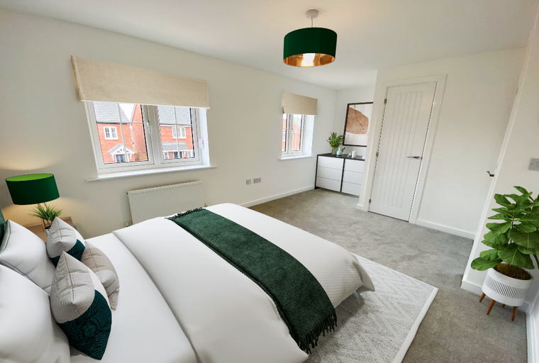 A bedroom with a bed, pillows, a throw, windows, a dresser, a pendant light, and a plant.