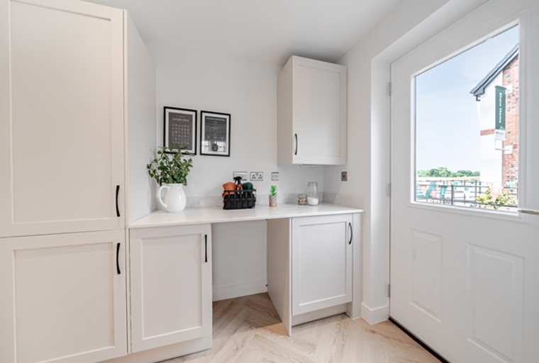 A utility room with white cabinets, a countertop, and a glass door.