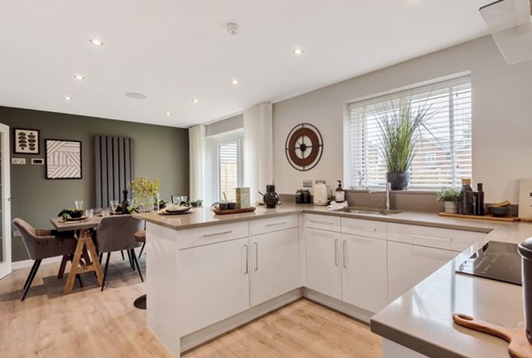 A modern kitchen and dining area with white cabinets, a dining table, and chairs.