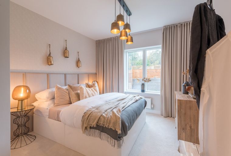 A bedroom with a bed, bedside lamps, and a window.