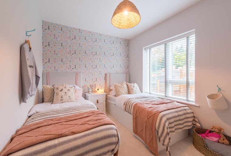 A bedroom with two twin beds, patterned wallpaper, and a large window.