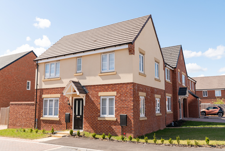 A modern two-story house with red brick and cream render exterior, featuring multiple windows and a black front door.