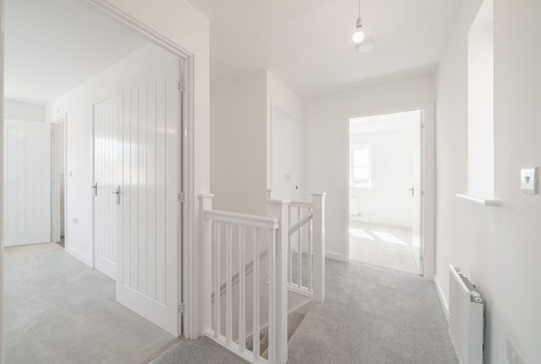A hallway with a staircase and multiple doorways.