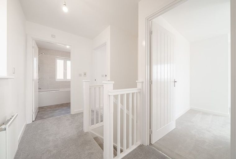 A hallway with a staircase, a bathroom, and a doorway.