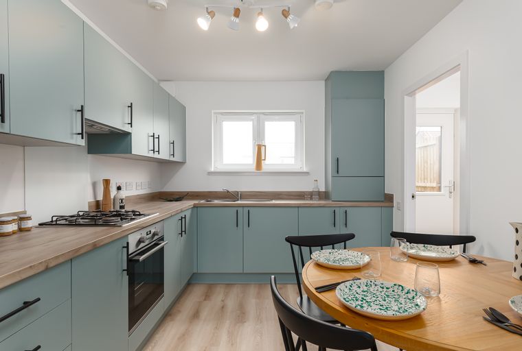 A kitchen and dining area with light blue cabinets, a wooden countertop, and a round dining table.