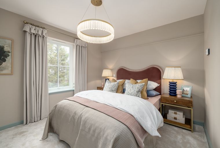 A bedroom with a bed, bedside tables, and a window.