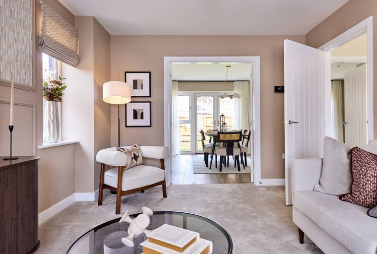 A living room with a sofa, armchair, coffee table, and a doorway leading to a dining room.