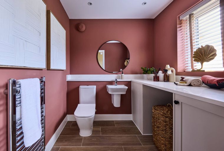 A bathroom with a toilet, sink, mirror, and towel warmer.