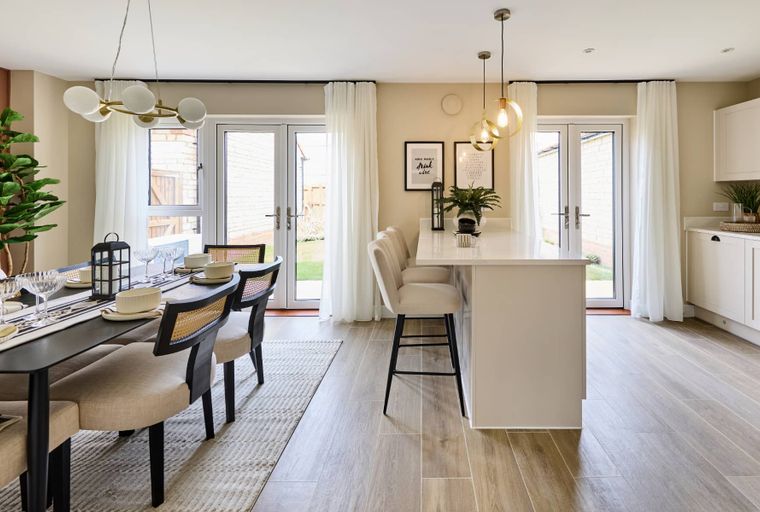 A dining area and kitchen island with pendant lights and chairs.