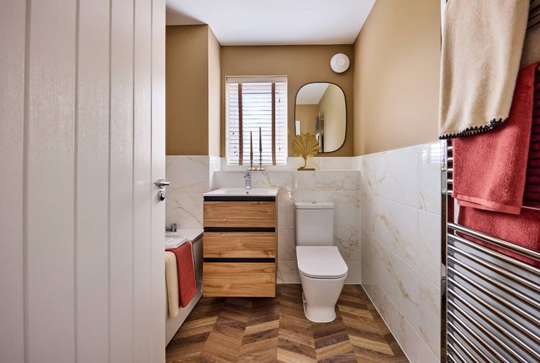 A bathroom with a wooden vanity, a toilet, a bathtub, and a towel warmer.