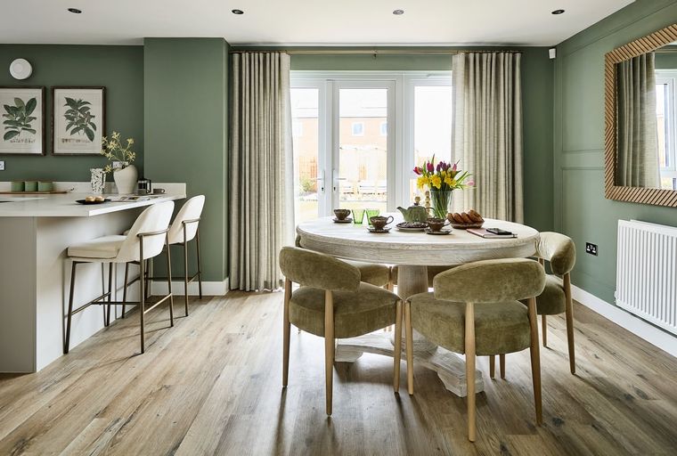 A dining area with a round table, chairs, and a kitchen island.