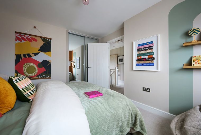 A bedroom with a bed, pillows, a tapestry, and a framed print.