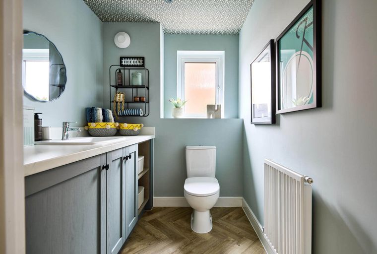 A bathroom with a vanity, toilet, and patterned ceiling.