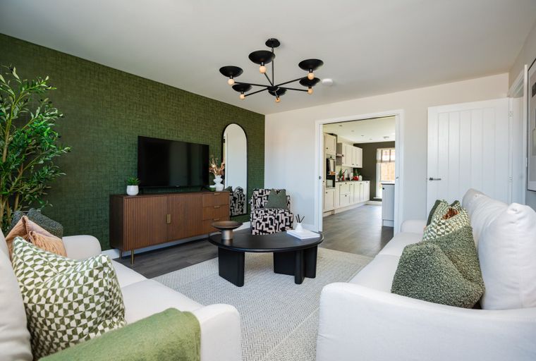 A living room with white sofas, a coffee table, and a textured green accent wall.