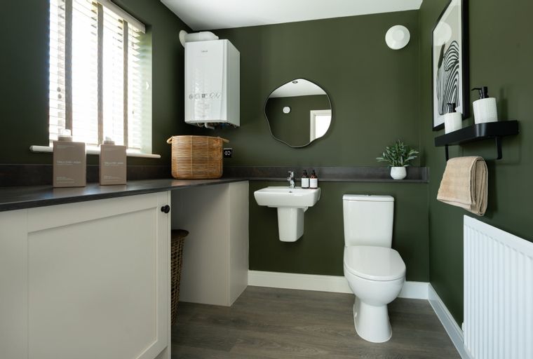A bathroom with a sink, toilet, and a wall-mounted boiler.