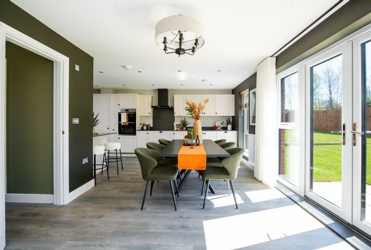 A dining area with a table and chairs next to a kitchen with cabinets and appliances.