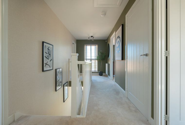 A hallway with doors, artwork, and a staircase.