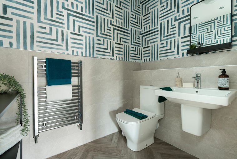 A bathroom with a toilet, sink, mirror, and heated towel rail.