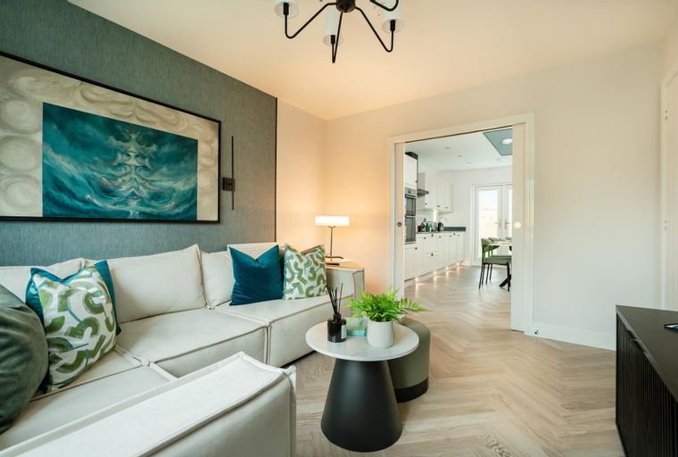 A living room with a sectional sofa, coffee table, and an open doorway to a kitchen.